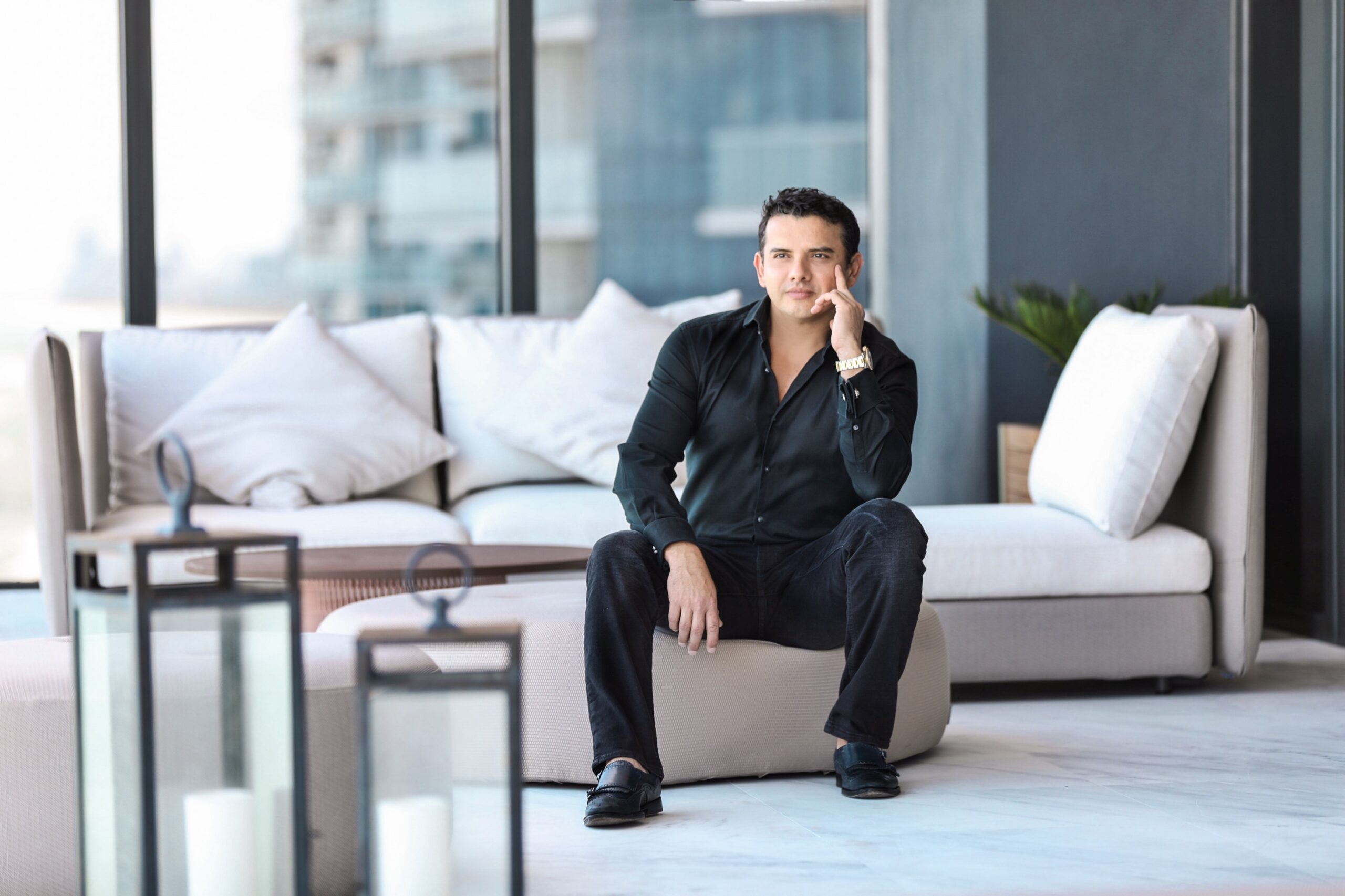 Businessman sitting thoughtfully on a suitcase in a modern living room.
