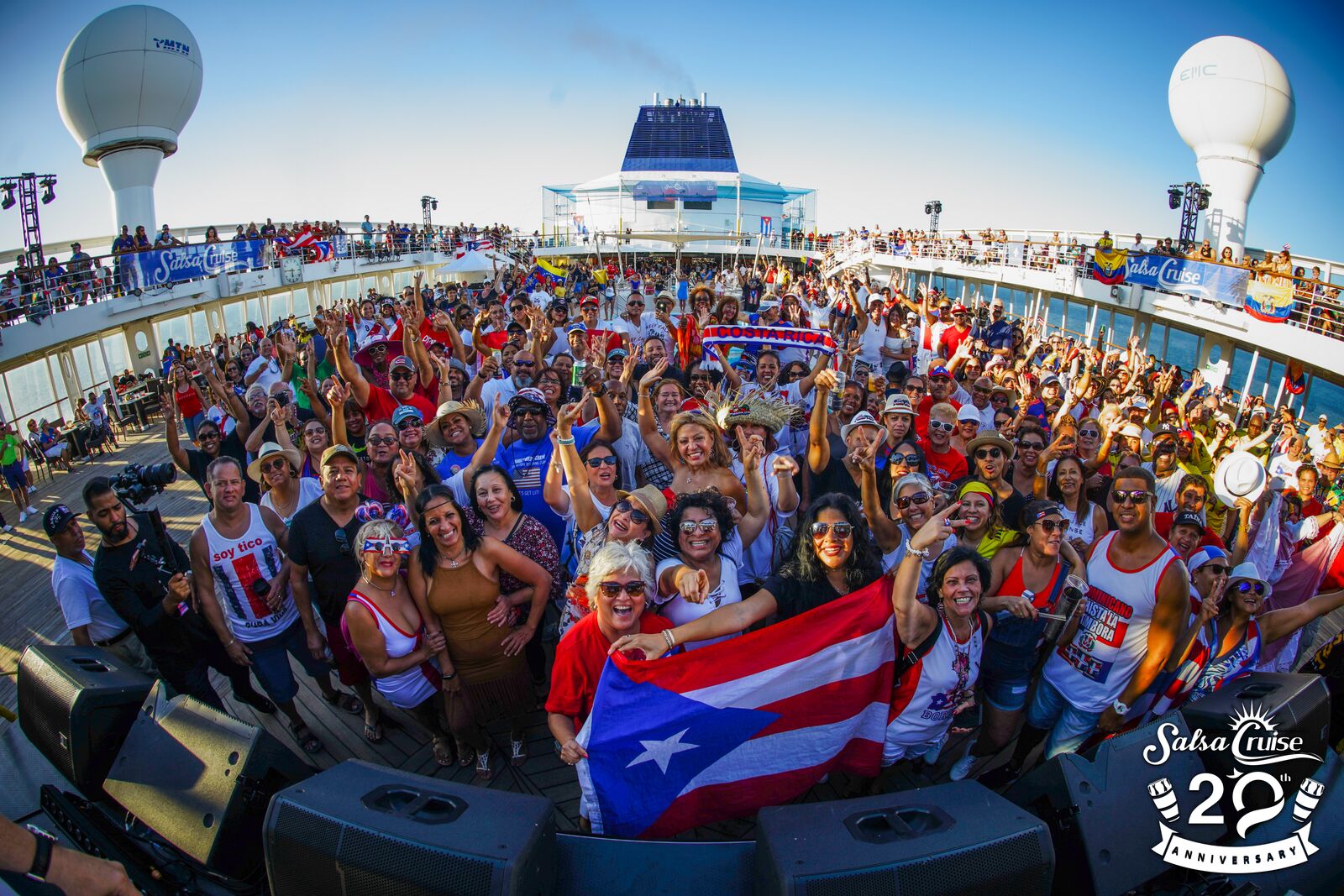 Crowd on a cruise ship deck waving a Puerto Rican flag.