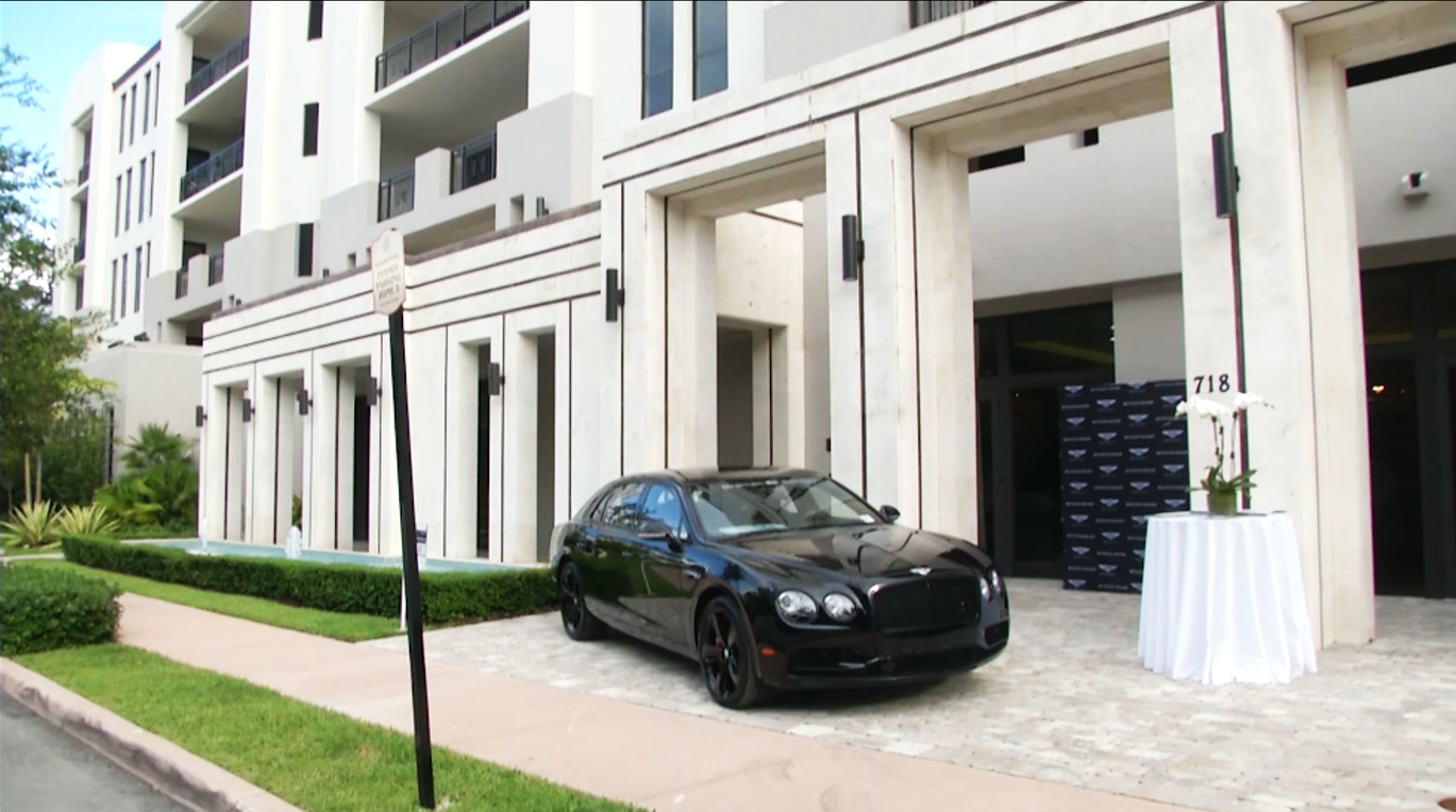 A sleek black sports car parked in a modern driveway.