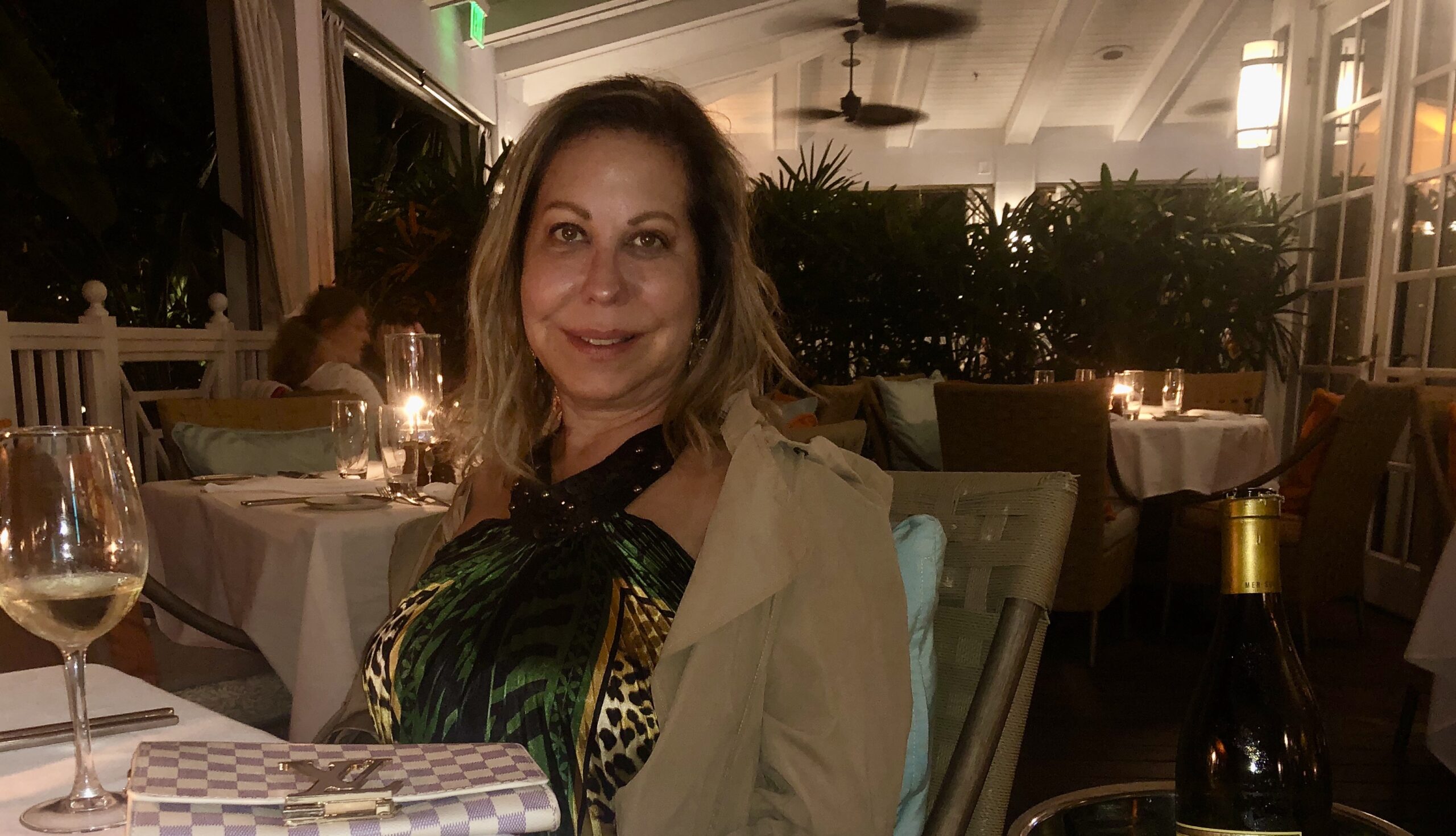 Woman smiling at a candlelit restaurant during the evening.