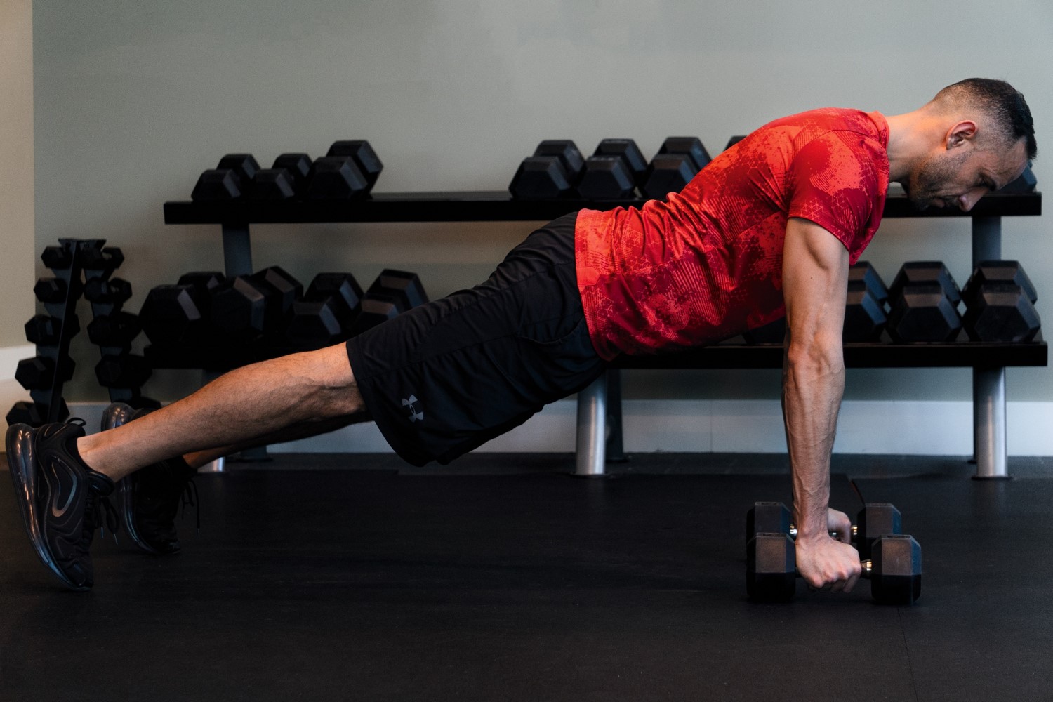 Man doing push-ups with dumbbells in a gym.