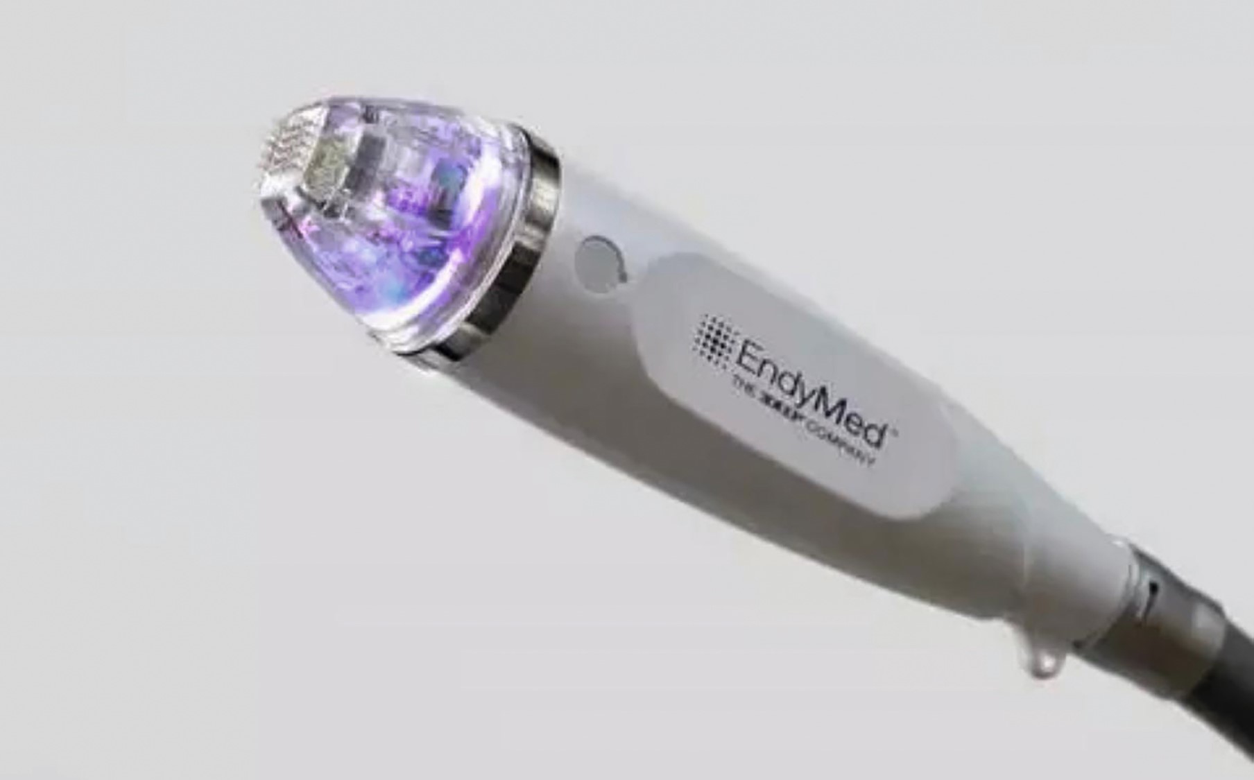 Close-up of a modern handheld skin treatment device with glowing purple light.