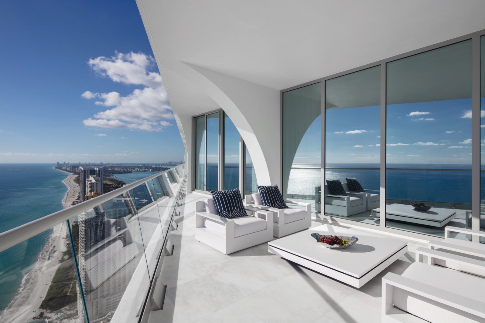 Modern balcony with ocean views and white furniture.