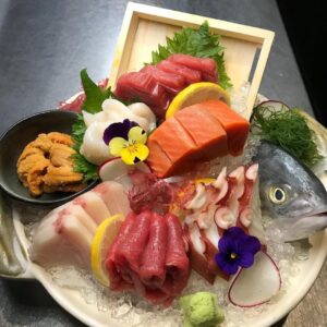 A vibrant sashimi platter with assorted fish and edible flowers.
