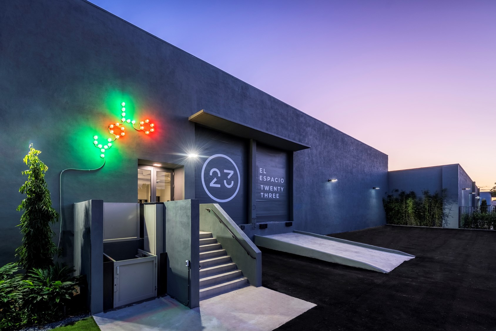Modern building exterior with neon lights at dusk.