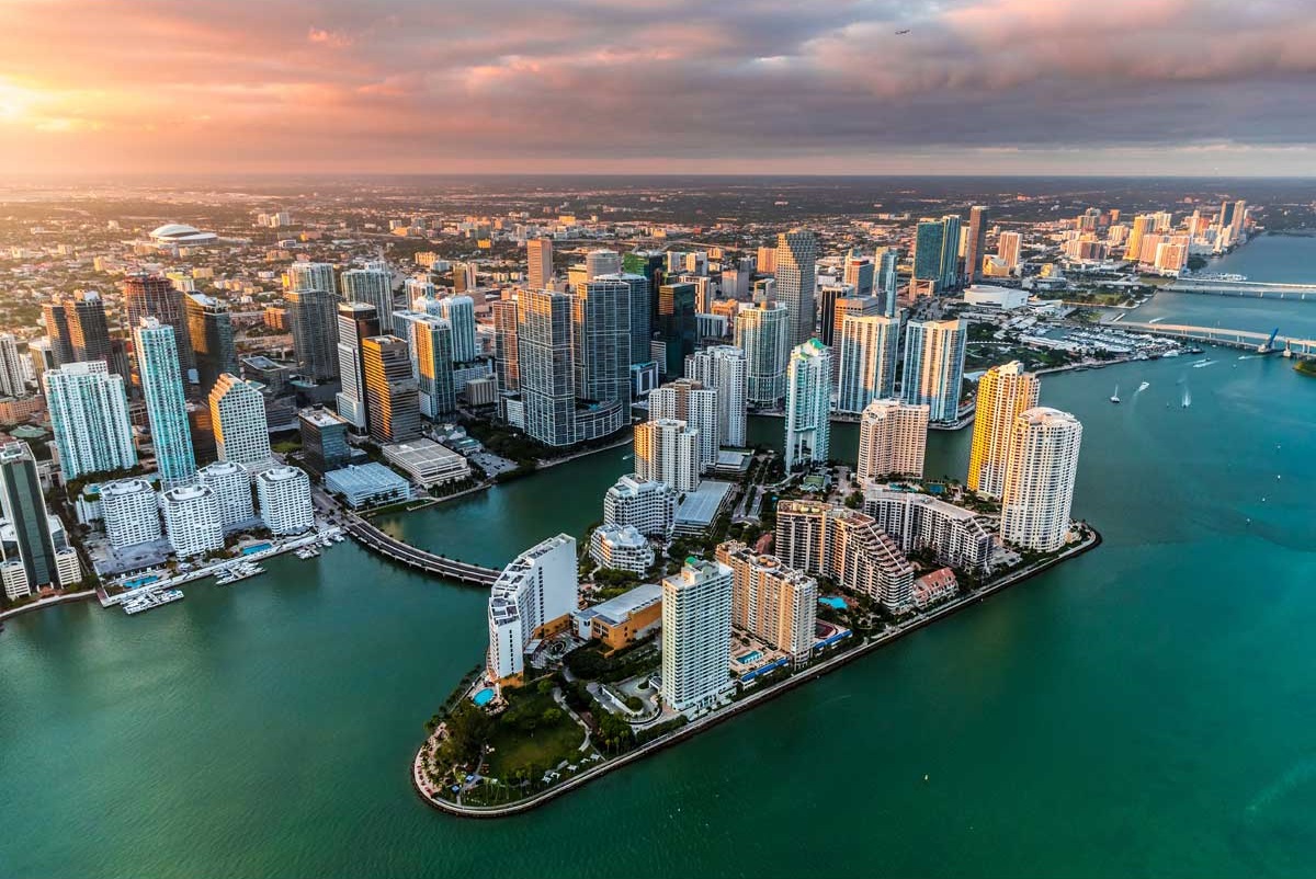 Aerial view of Miami's downtown skyline at sunset with waterways and tall buildings.