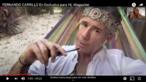 Man wearing a crown and holding a pen, looking at the camera.