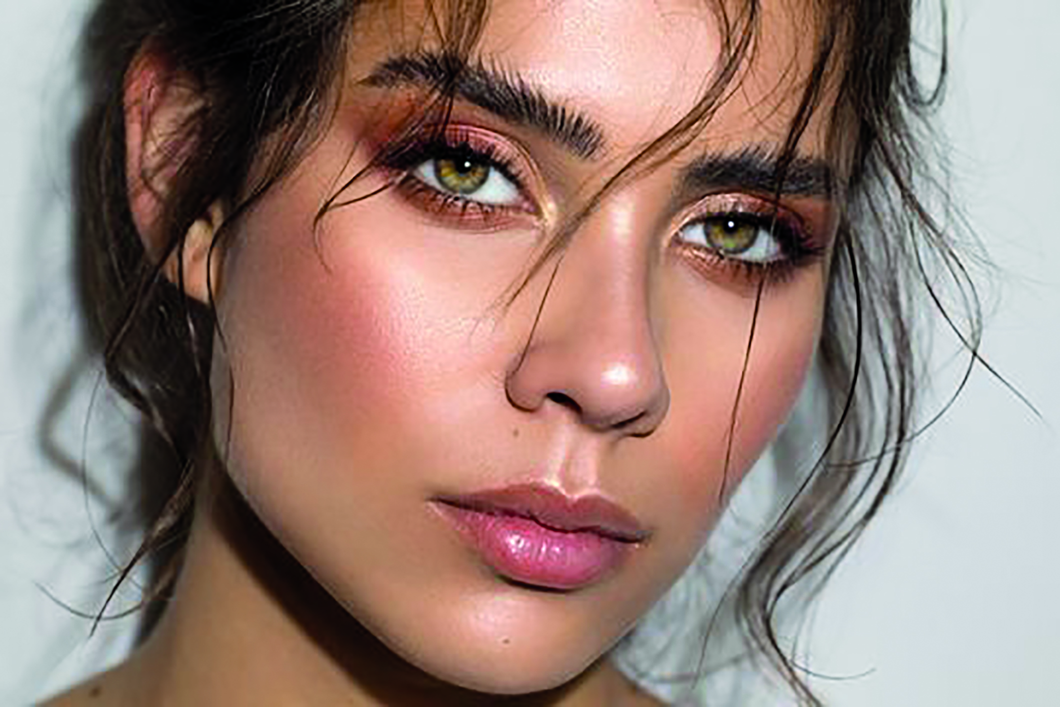 Close-up portrait of a woman with striking green eyes and natural makeup.
