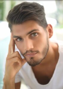 Close-up of a thoughtful young man with striking green eyes.