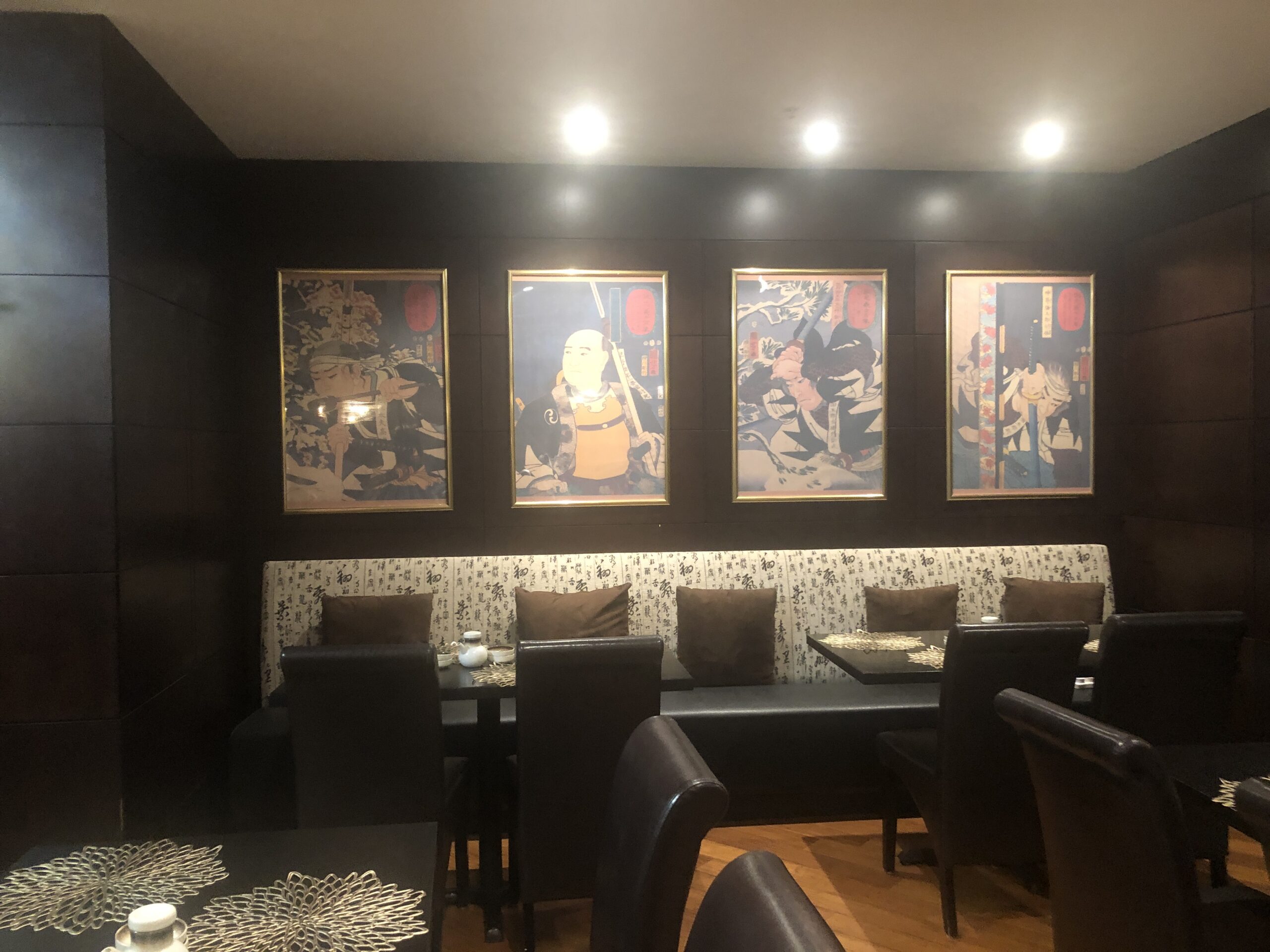 Cozy dining area with framed anime posters illuminated on the wall.