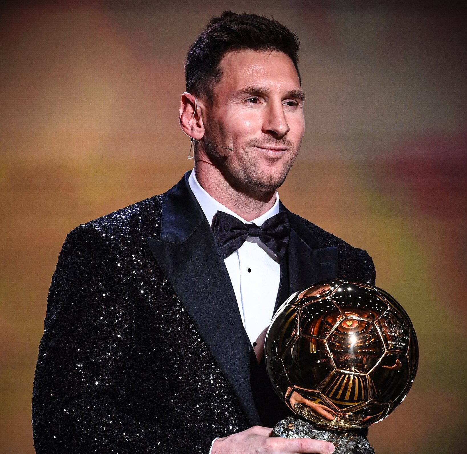 A man in a tuxedo holding a golden trophy.