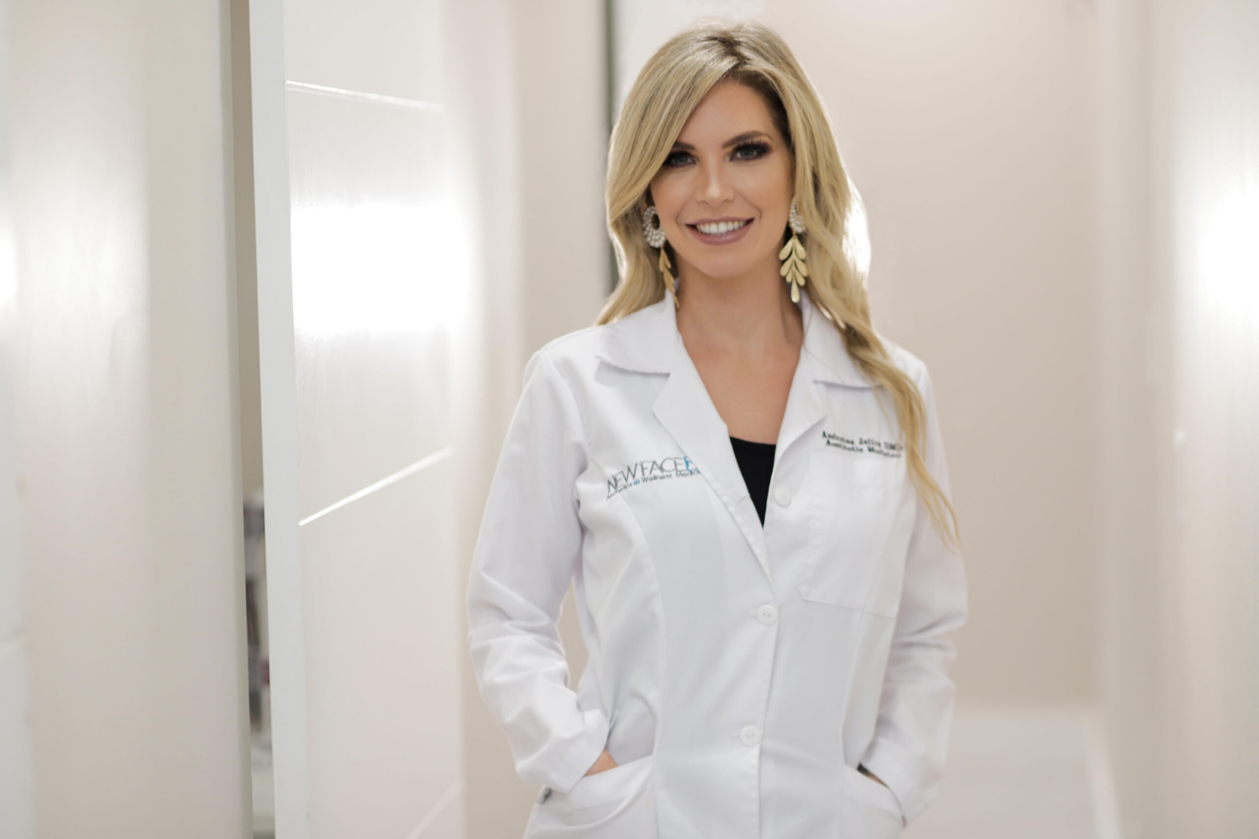 Smiling female doctor in white coat with hands in pockets.