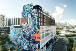 A tall building with vibrant blue and orange wave mural on its side.
