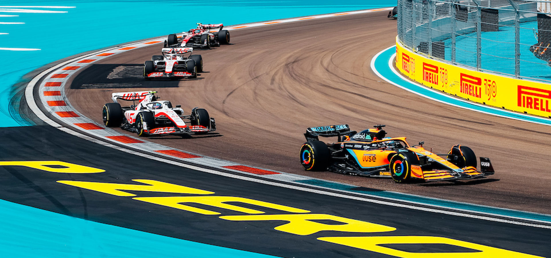 Three race cars navigating a sharp curve on a vibrant racetrack.