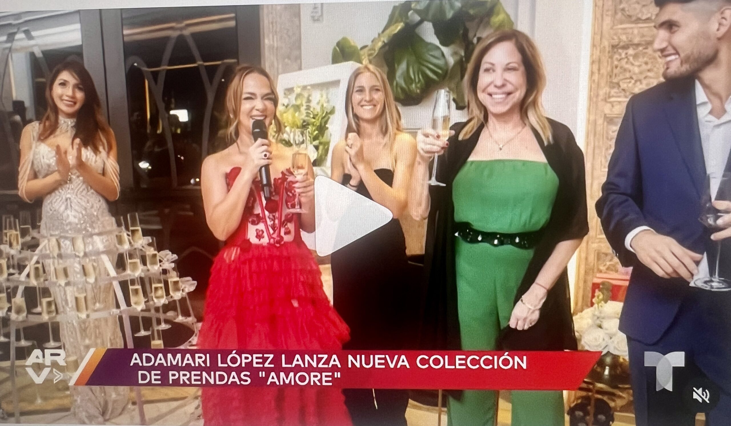 Three women smiling and toasting with drinks at a collection launch event.
