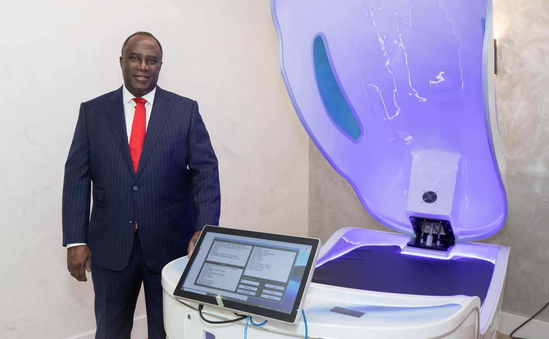 A man in a suit stands next to a futuristic medical device with a touchscreen.