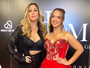 Two women dressed elegantly in black and red at a formal event.