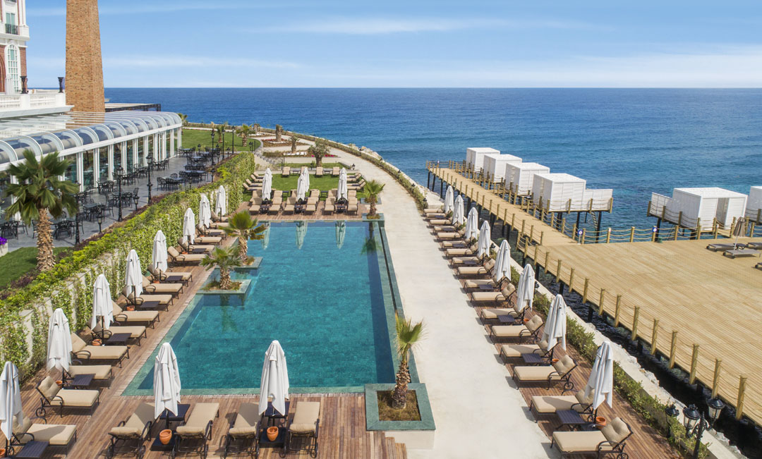 Elegant seaside resort pool with lounge chairs and cabanas.