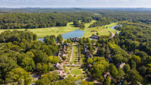 Aerial view of a scenic golf course surrounded by trees and houses.