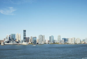 City skyline with buildings by the water under a clear blue sky.