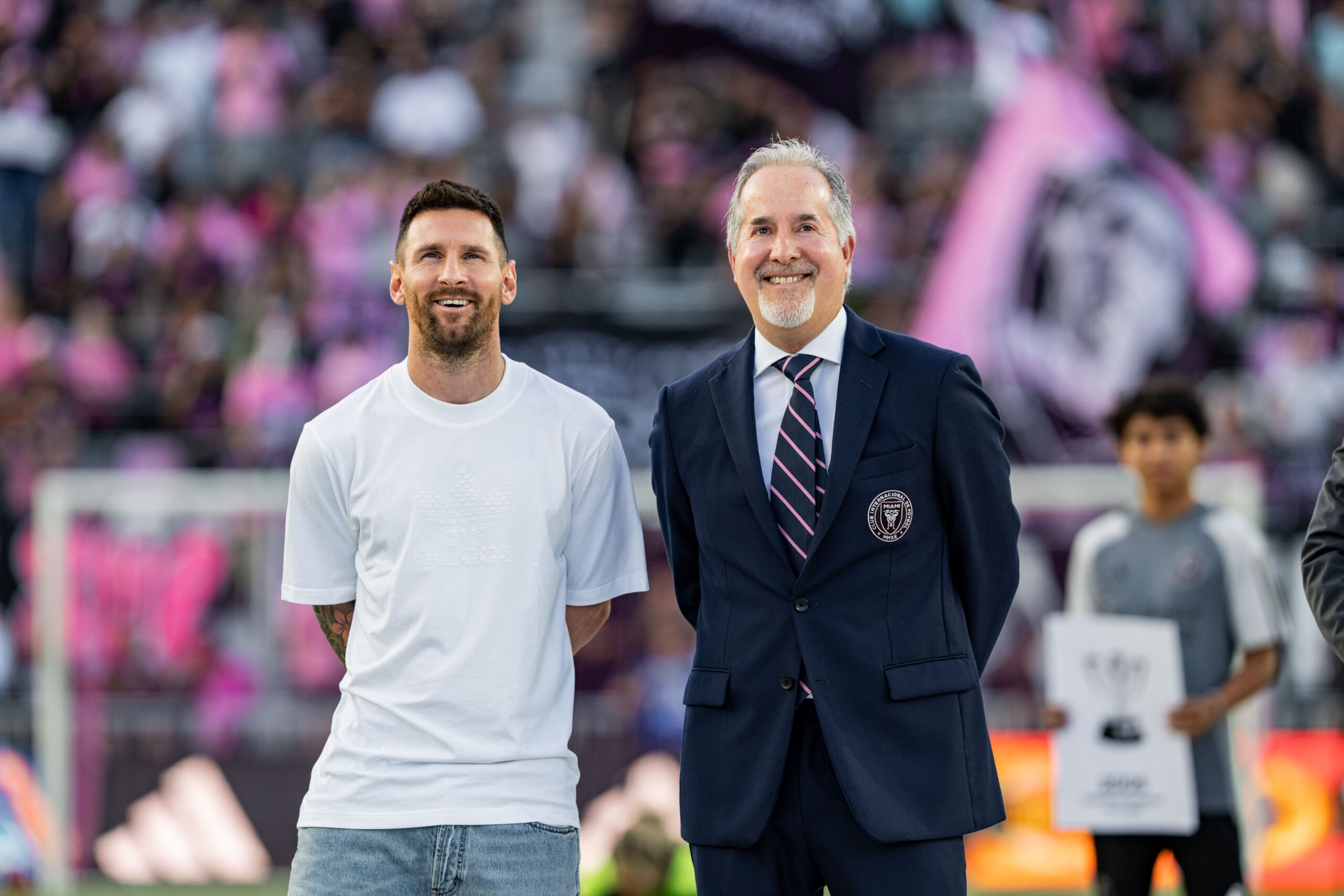 Lionel Messi standing beside a suited official at a stadium event.