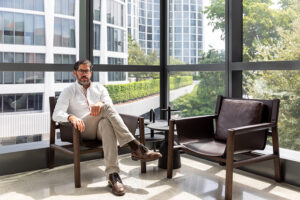 Man sitting in a modern office lounge with large windows and city view.