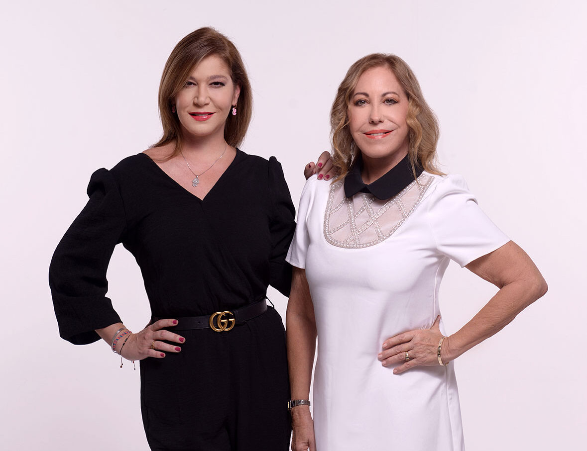 Two women posing confidently in black and white outfits against a plain background.
