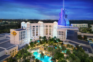 Luxurious hotel with illuminated pool and unique guitar-shaped building at night.