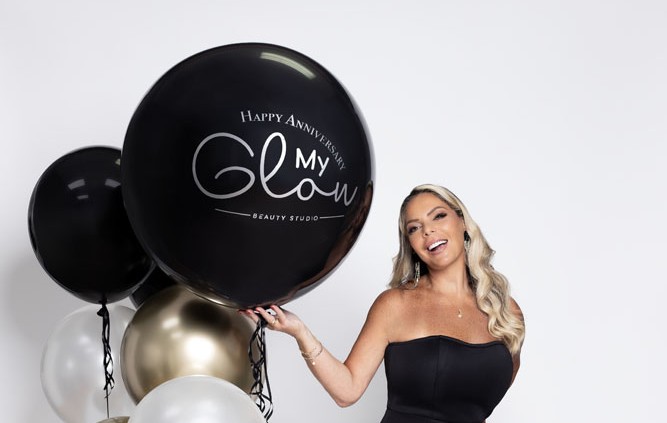 My Glow Beauty Studio founder with anniversary balloons