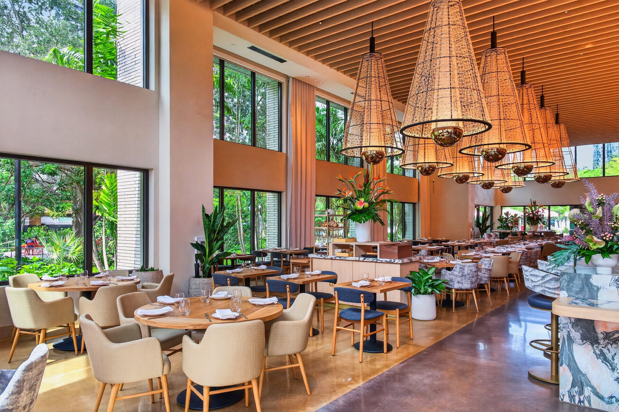 Salón de Sweetwaters con ventanales de piso a techo y vegetación