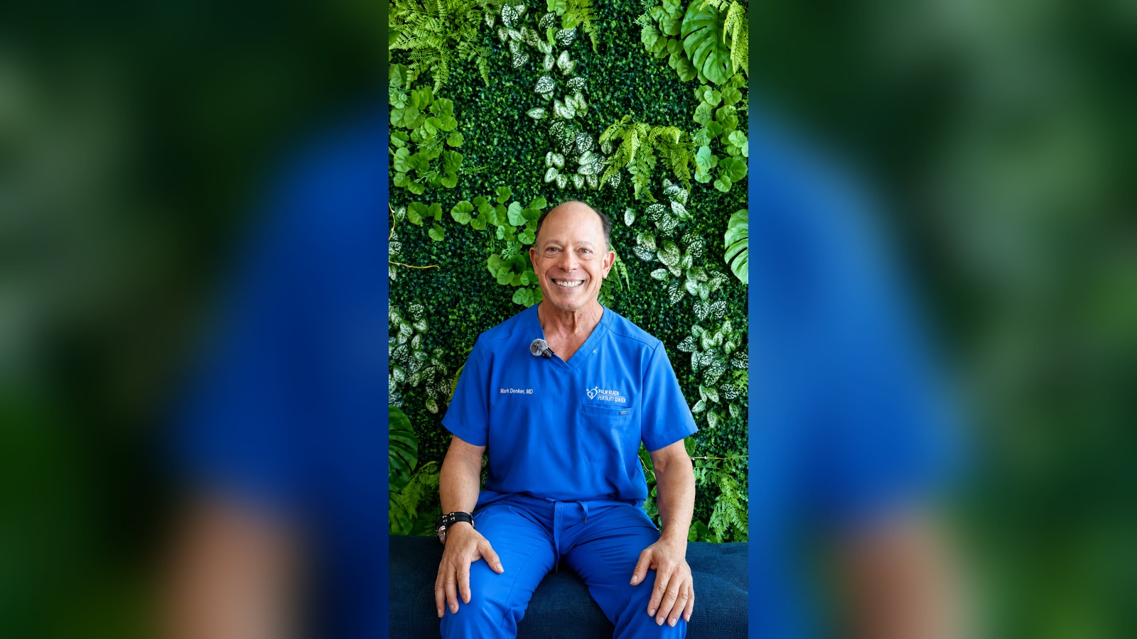 Dr. Mark S. Denker, reproductive endocrinologist, seated in front of a green plant wall