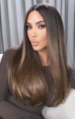 A woman with long straight brown hair posing indoors.