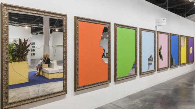 Art gallery with large framed colorful abstract paintings on white walls.