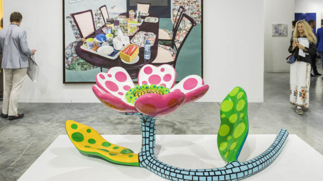 Colorful flower sculpture with a painted stem and leaves in an art gallery.
