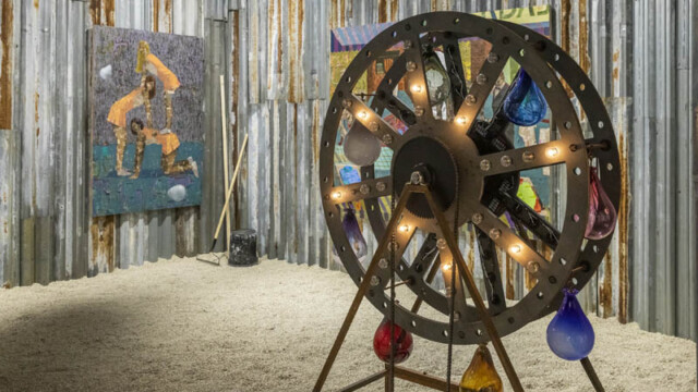 Rustic indoor scene with a large wooden wheel and festive lights.