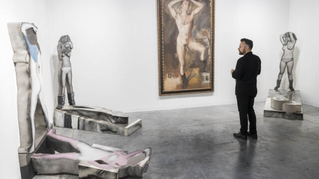 A man observing sculptures and a painting in a modern art gallery.