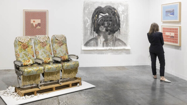 Art gallery with abstract portraits and vintage theater seats on display.