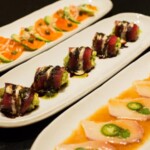 Elegant sushi and sashimi dishes artfully arranged on white plates.