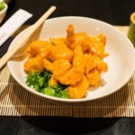 Crispy battered shrimp served on a bed of greens with dipping sauce.