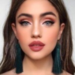 Close-up of a woman with striking makeup and long earrings.