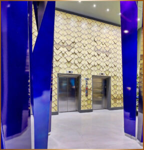 Modern lobby with sleek elevators and artistic stone wall.