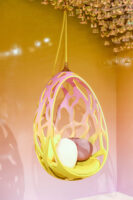 A colorful hanging chair with cushions inside against a warm background.