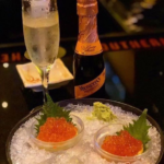Elegant champagne and caviar served on ice with garnish.
