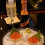 Elegant champagne and caviar served on ice with garnish.