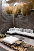 Modern outdoor seating area with white cushions and potted plants.
