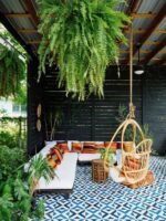 Cozy outdoor seating area with hanging plants and swing chairs.