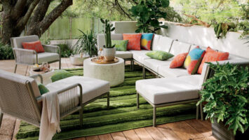 Elegant outdoor patio with white furniture and colorful cushions on a green rug.