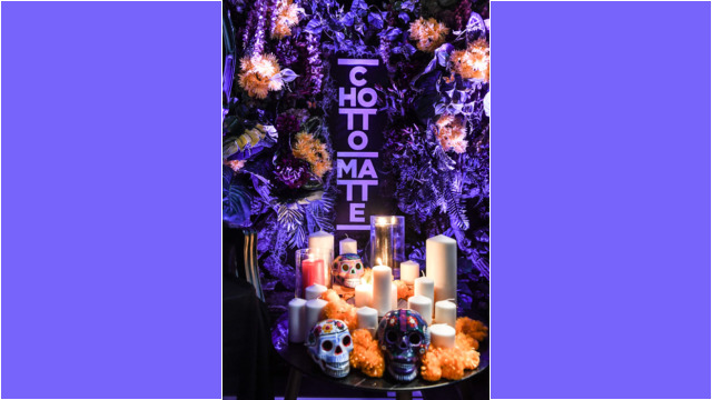Candles and flowers surround a skull in a colorful altar.
