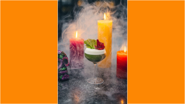 Colorful candles and a festive cocktail surrounded by mist, evoking a spooky atmosphere.