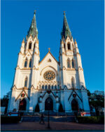 Gothic-style church with twin spires under a clear blue sky.